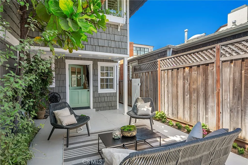 patio with wicker chairs and cushions around a low table on a striped rug