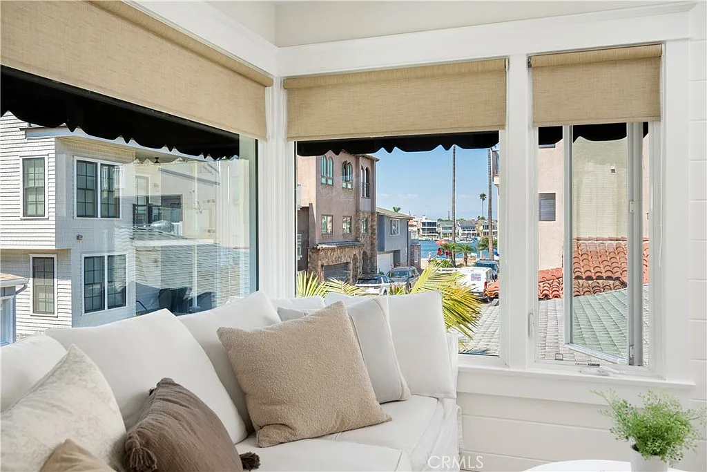 white sofa with beige pillows by a large corner window.