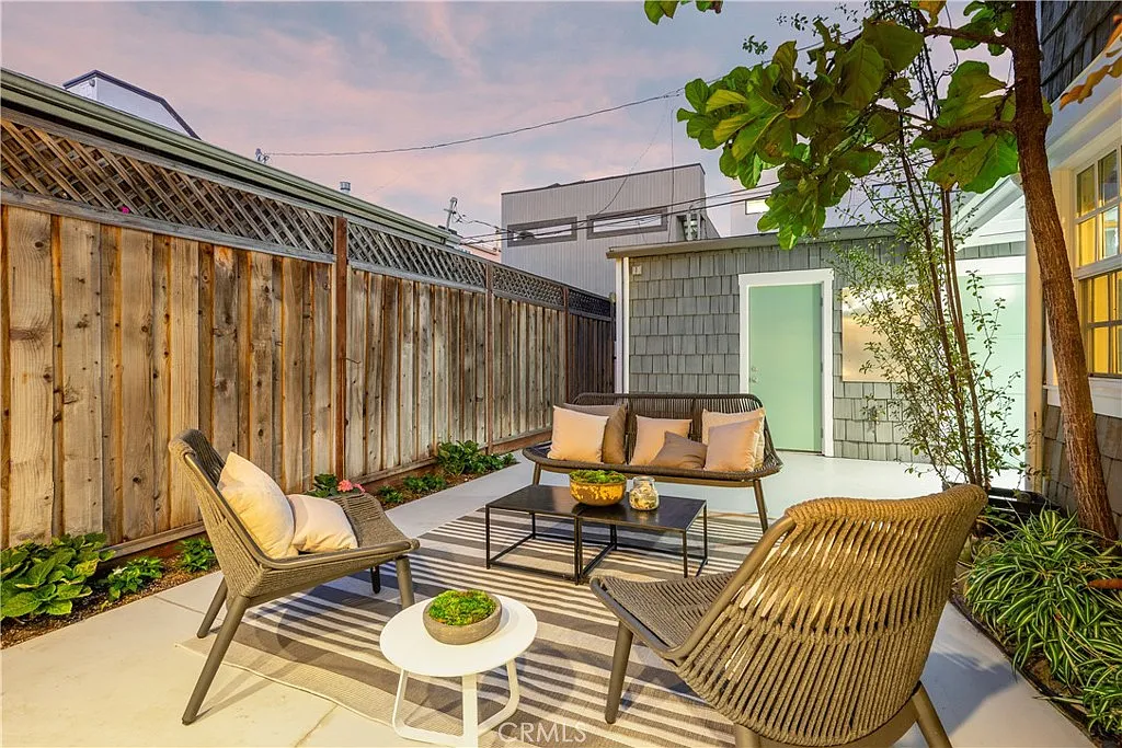 patio with wicker chairs, a gray sofa, and a striped rug